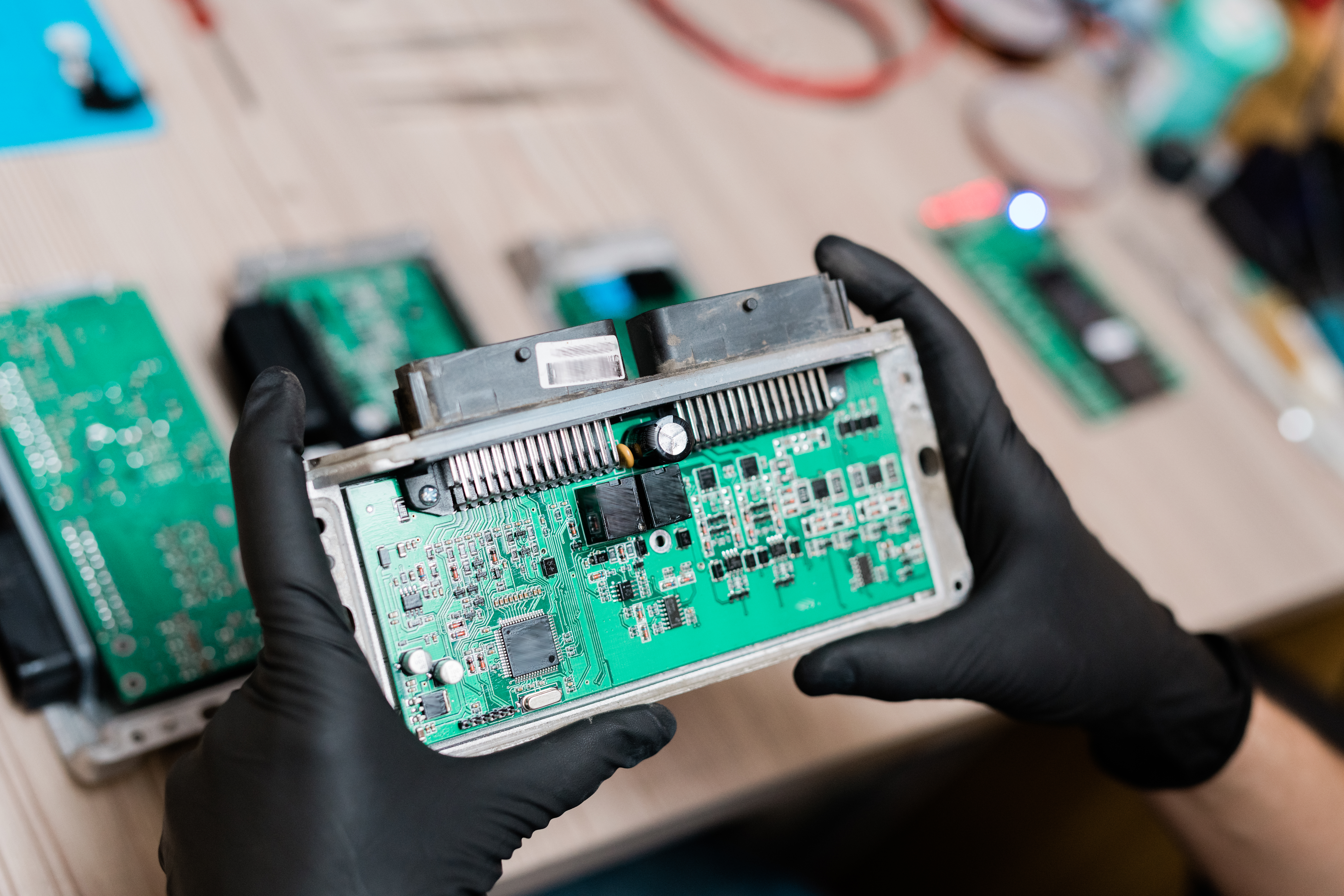 Gloved hands of repair service master holding part of demounted gadget while examining it and trying to find out cause of breakage